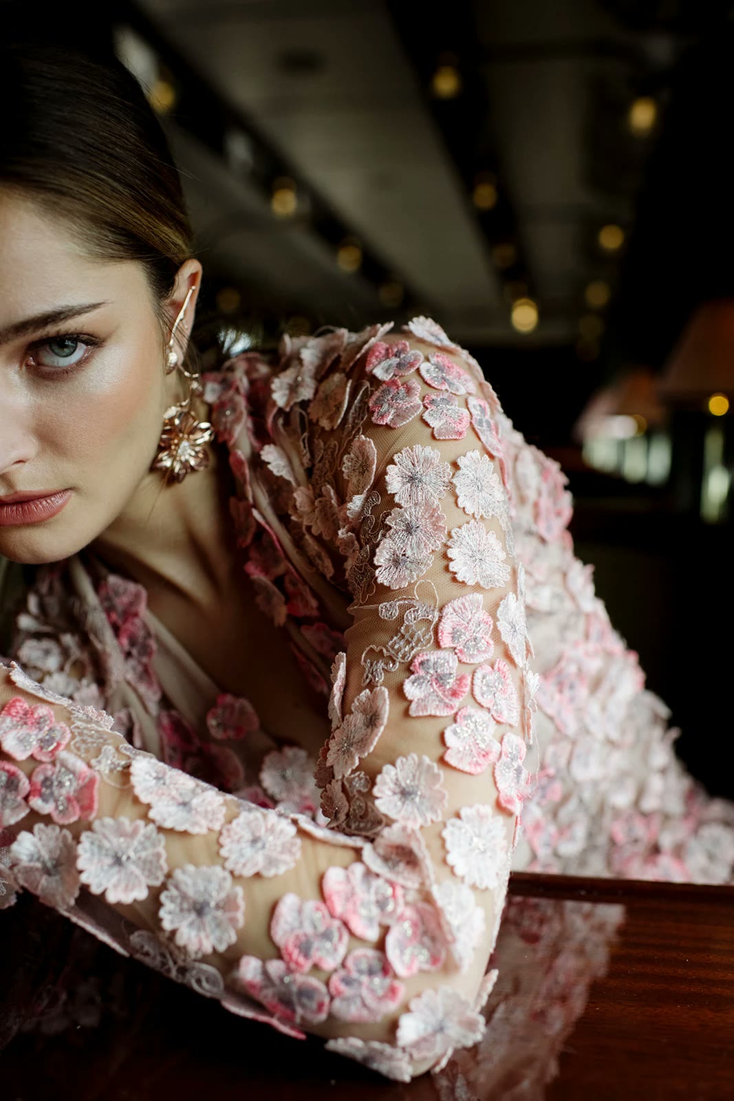 Bride in a gown of pink floral appliqués resting on lacquered wood aboard the Orient Express, photographed by Thierry Joubert